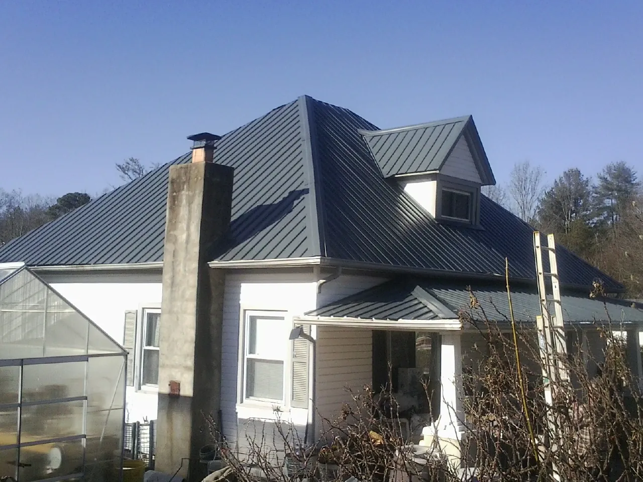 Dark blue standing seam metal roof on a white farmhouse with dormer — Slate & Tile Roof Repair by Roofing Brothers in Eastport