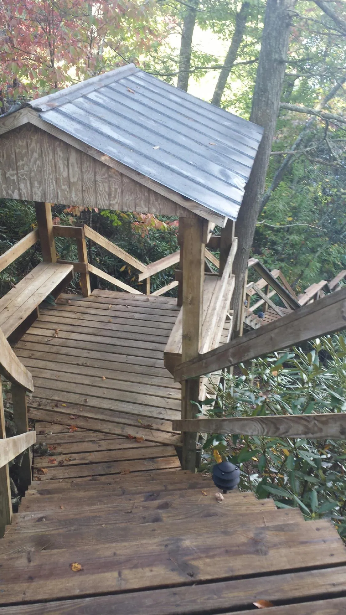 Metal roofed shelter over wooden steps on a wooded walkway — Skylight Repair & Installation work by our crew in Eastport